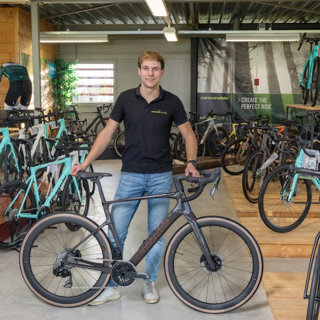 Medewerker van Scholten Cycling bij een donkergrijze Cannondale-racefiets in de showroom in Dalen
